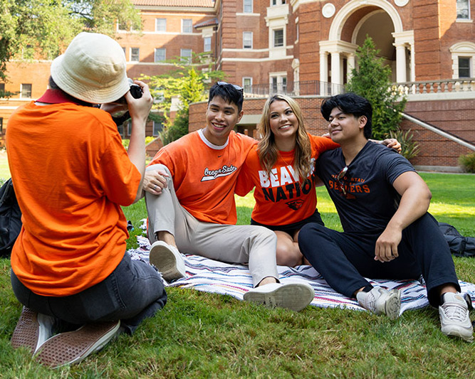 students sitting in grass with Weatherford Hall in background