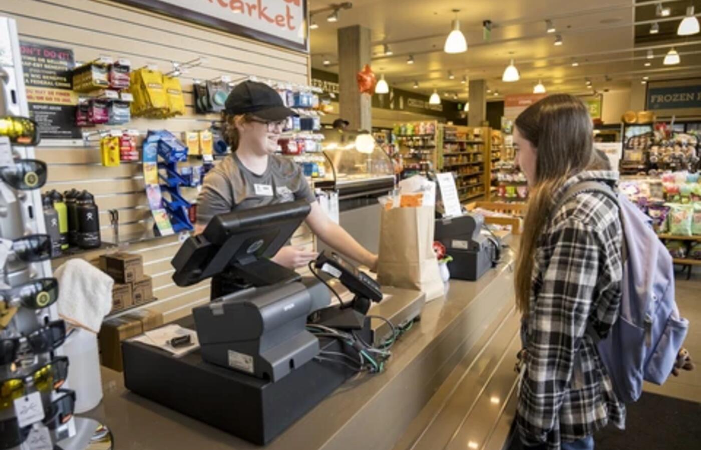 A A student worker assists a customer at checkout in Cascadia Market