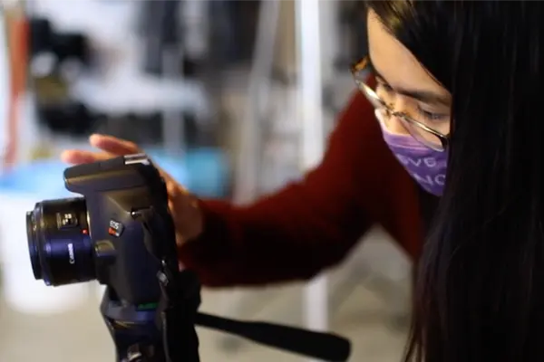 Student looks at a camera on a tripod.